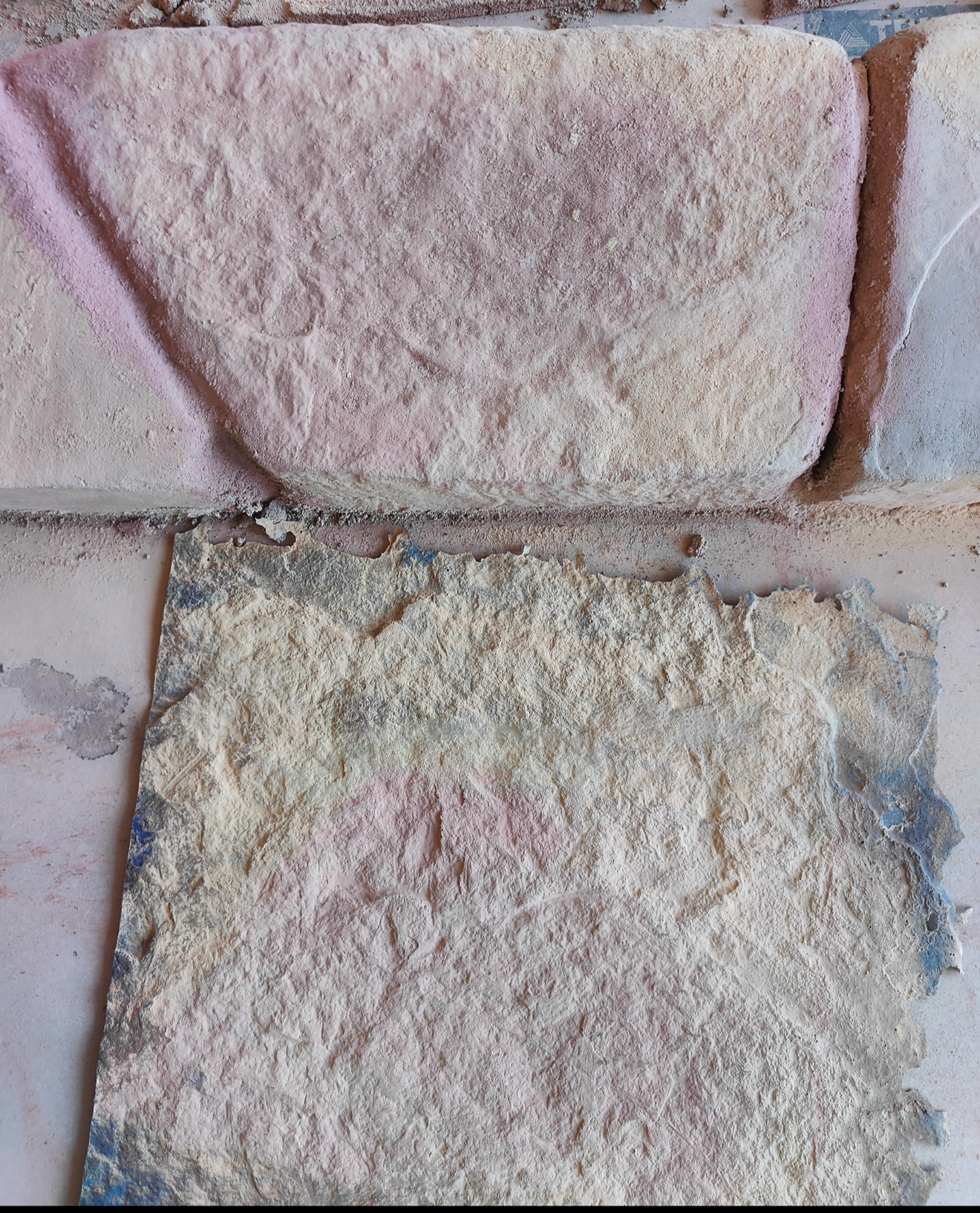 close-up of a blue stone stamp with a natural stone texture placed below real stone surface. The stamp captures the stone's details, including deep indentations. The image highlights the comparison between he stamped concrete impression and the original stone texture.