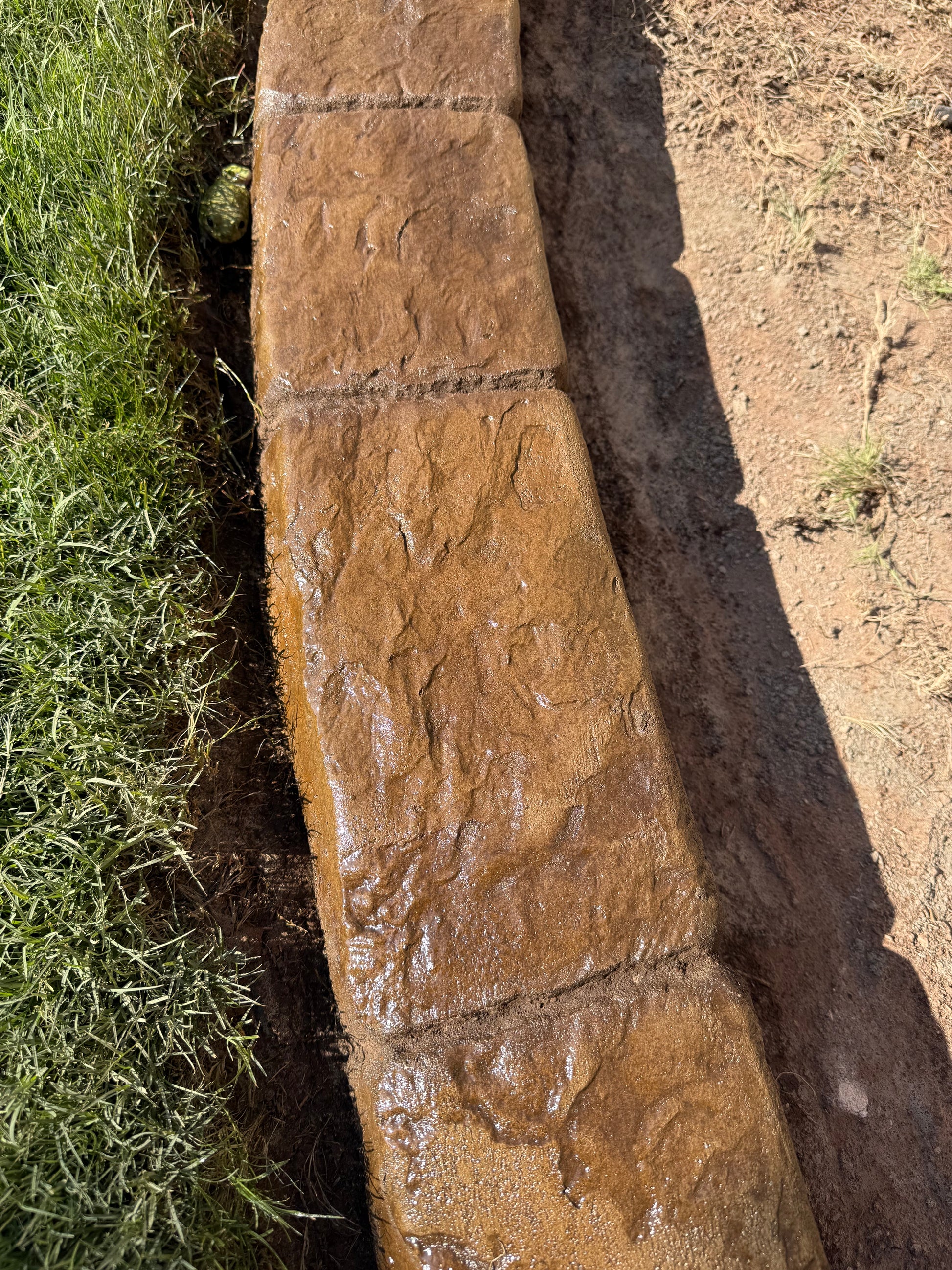 Stone curb with grass at the edge.
