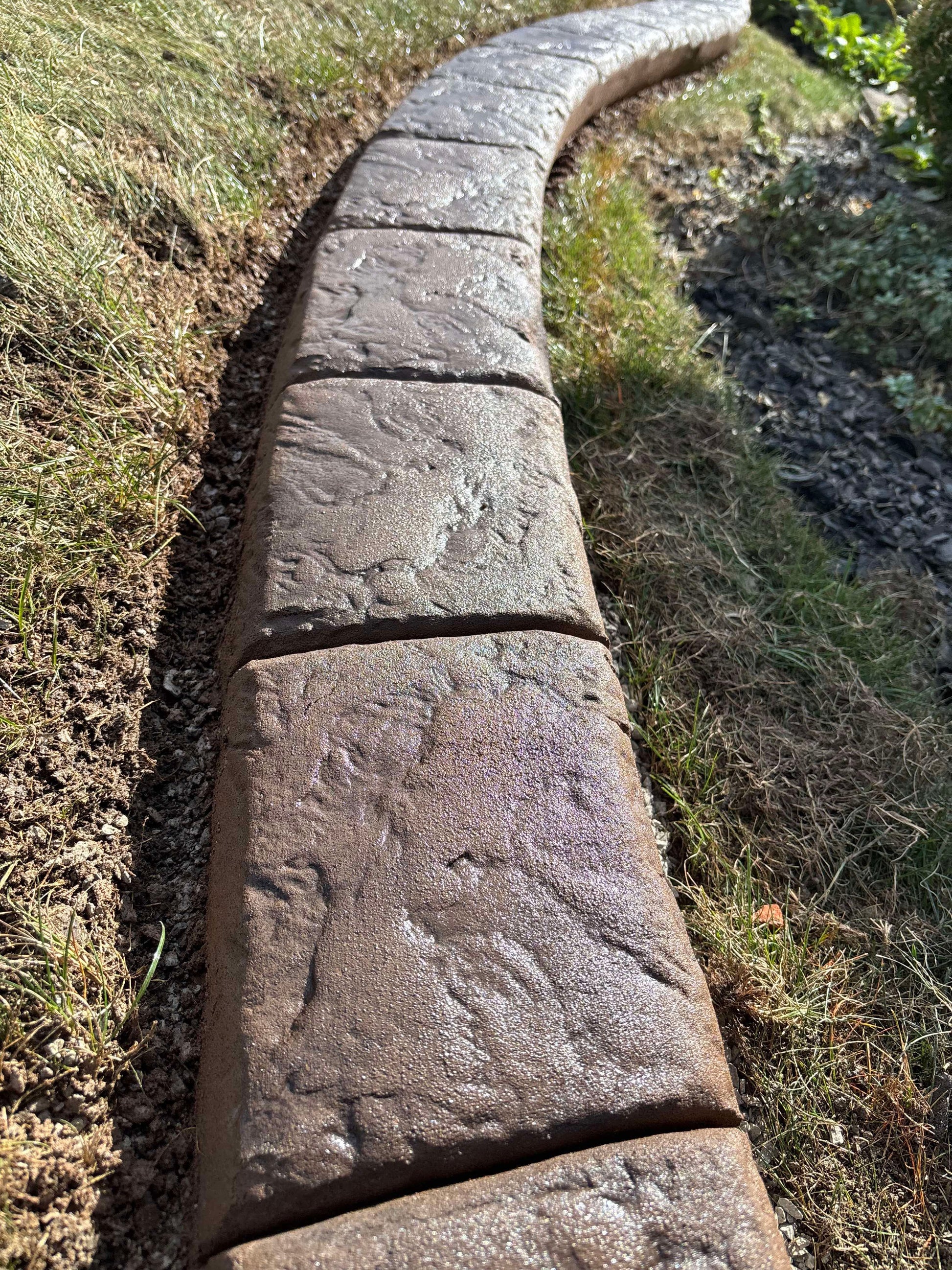 Row of stone bricks laid out on a grassy area