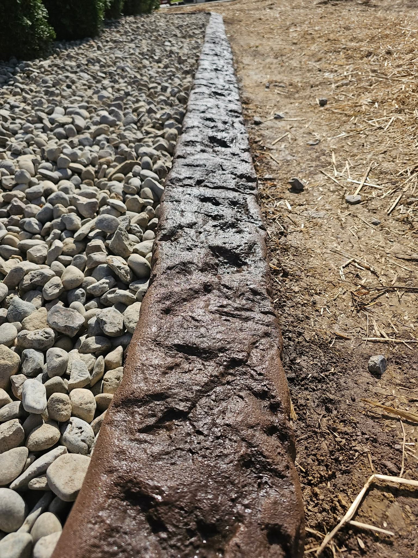 Long, narrow stone slab with the gabbro texture  on a dirt and gravel surface