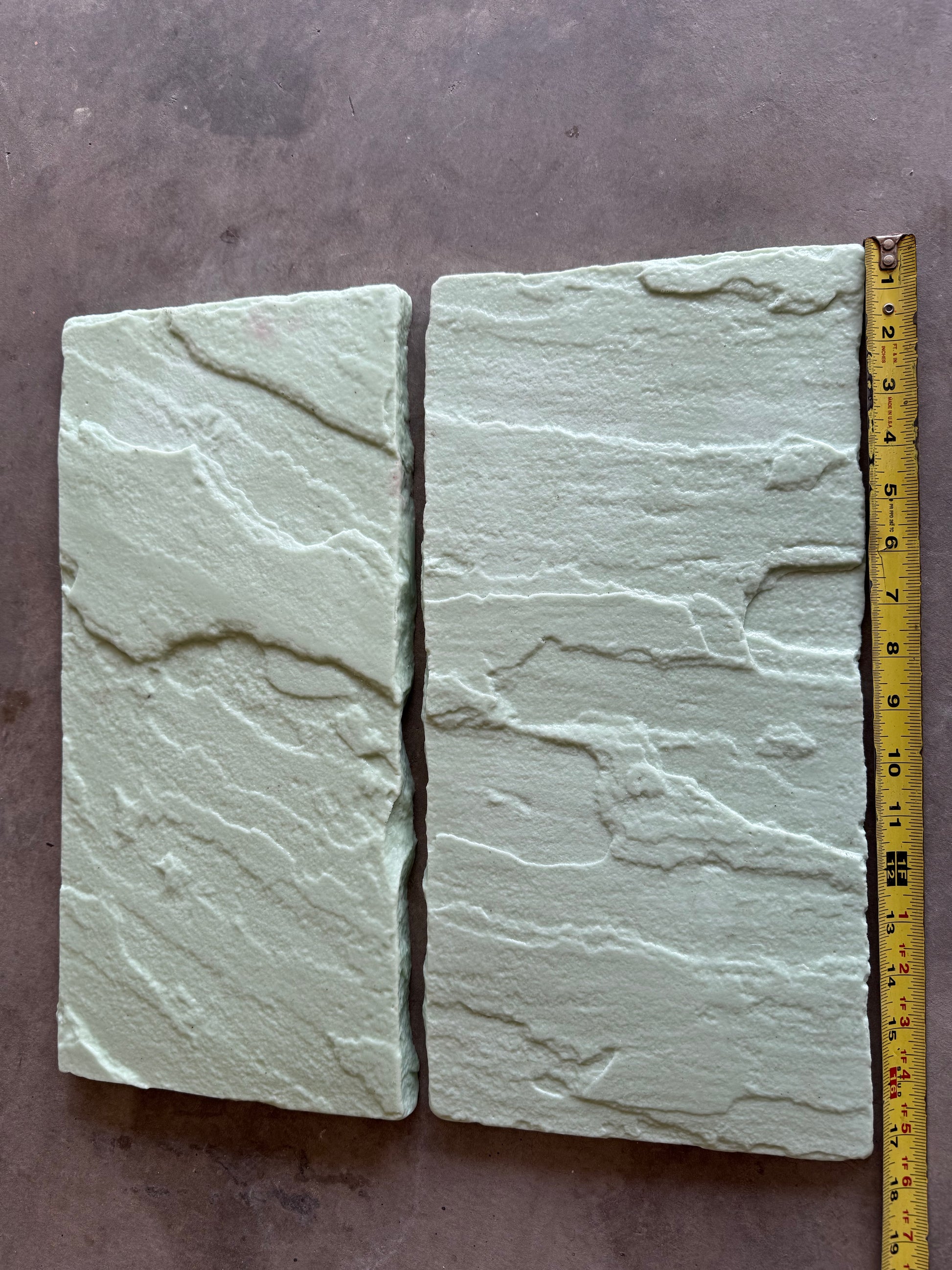 Two Mesa Slate stone with a measuring tape for scale on a dark surface