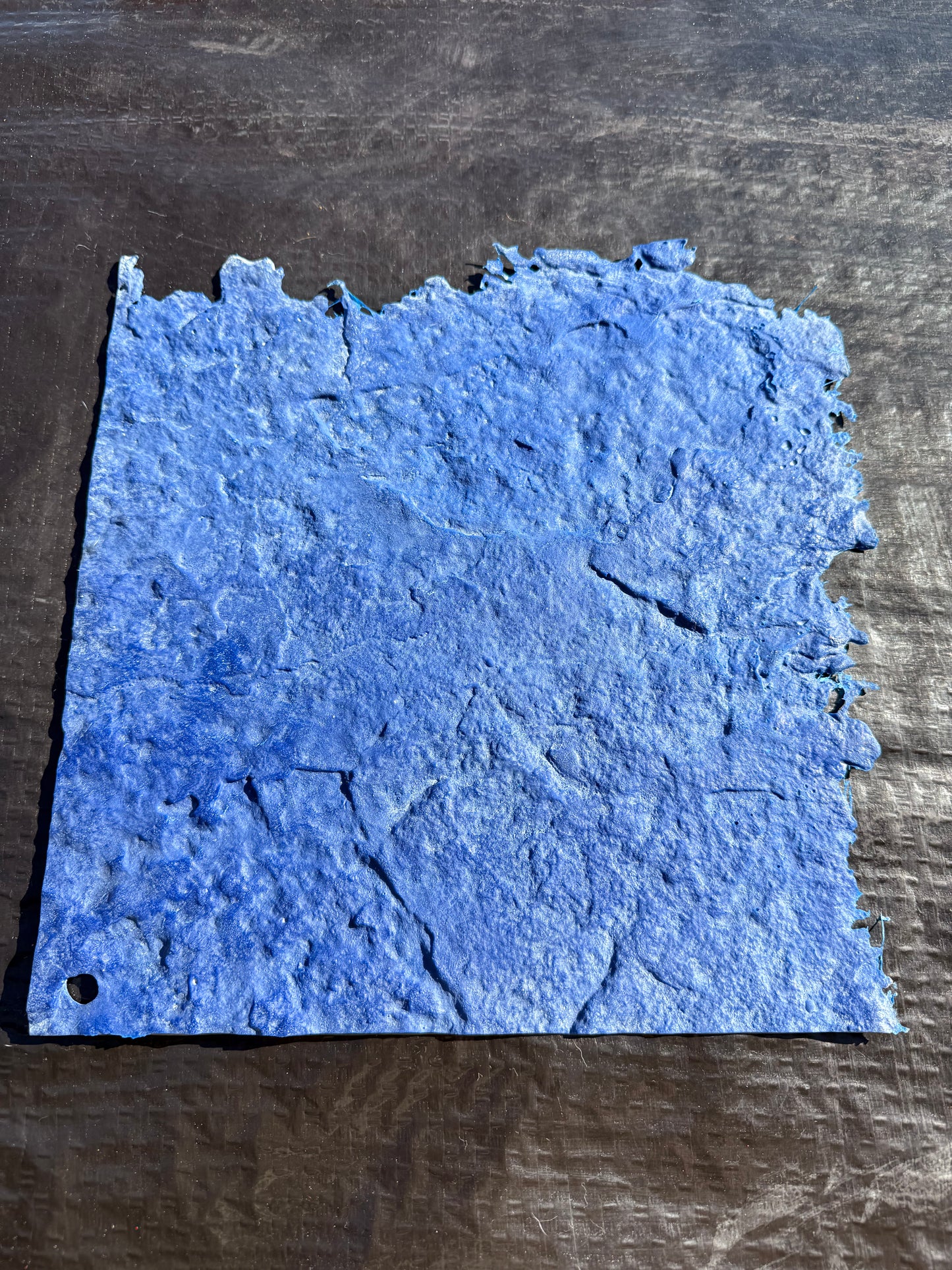 Blue textured square on a dark black surface