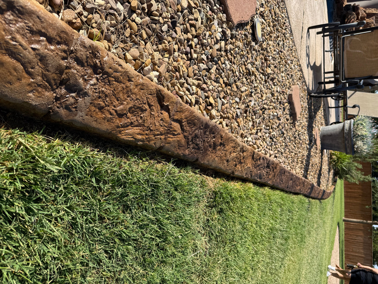 Grass border with a stone edge next to a paved path