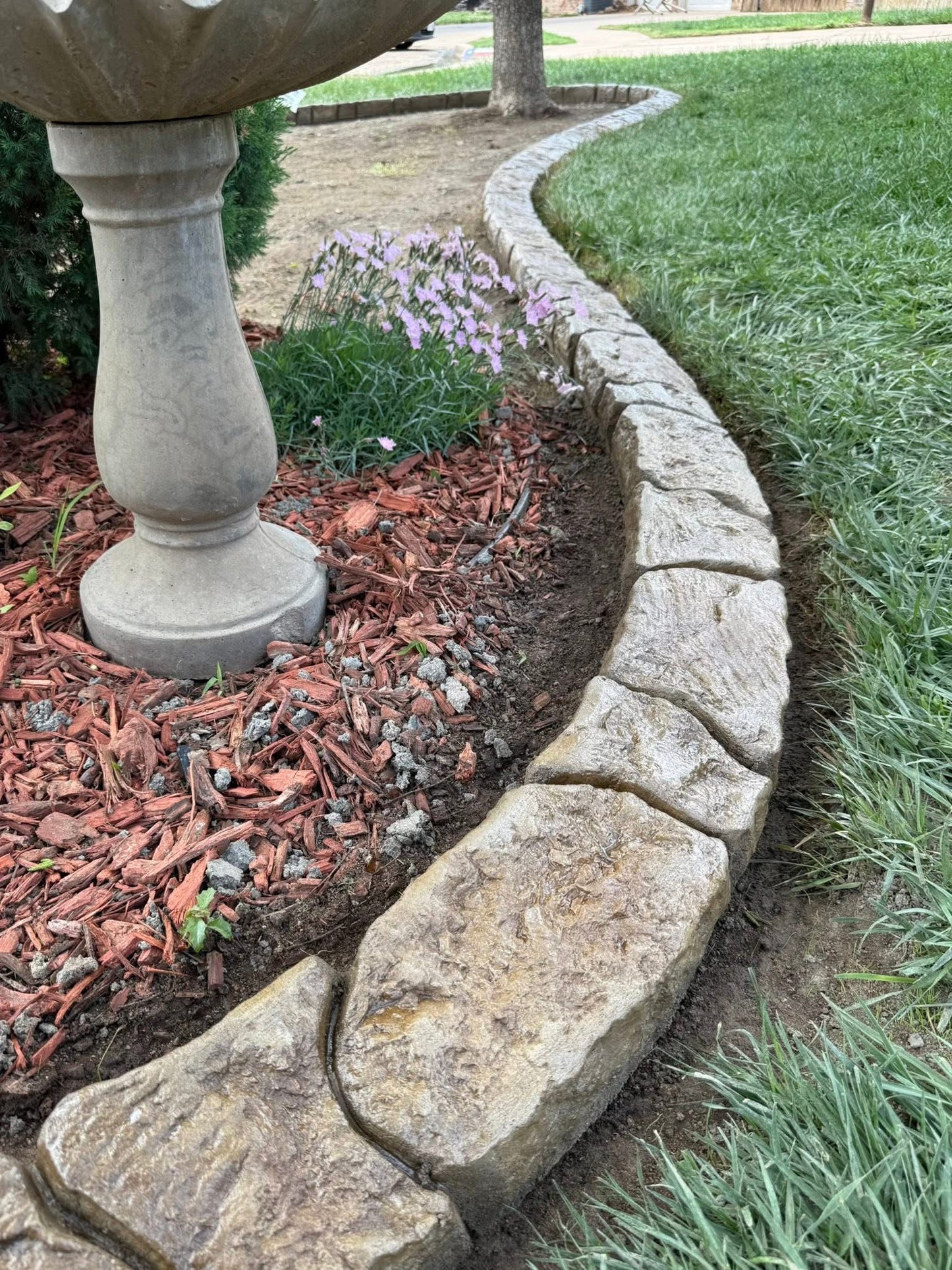 Curbing next to the grass with a flower bed inside of it