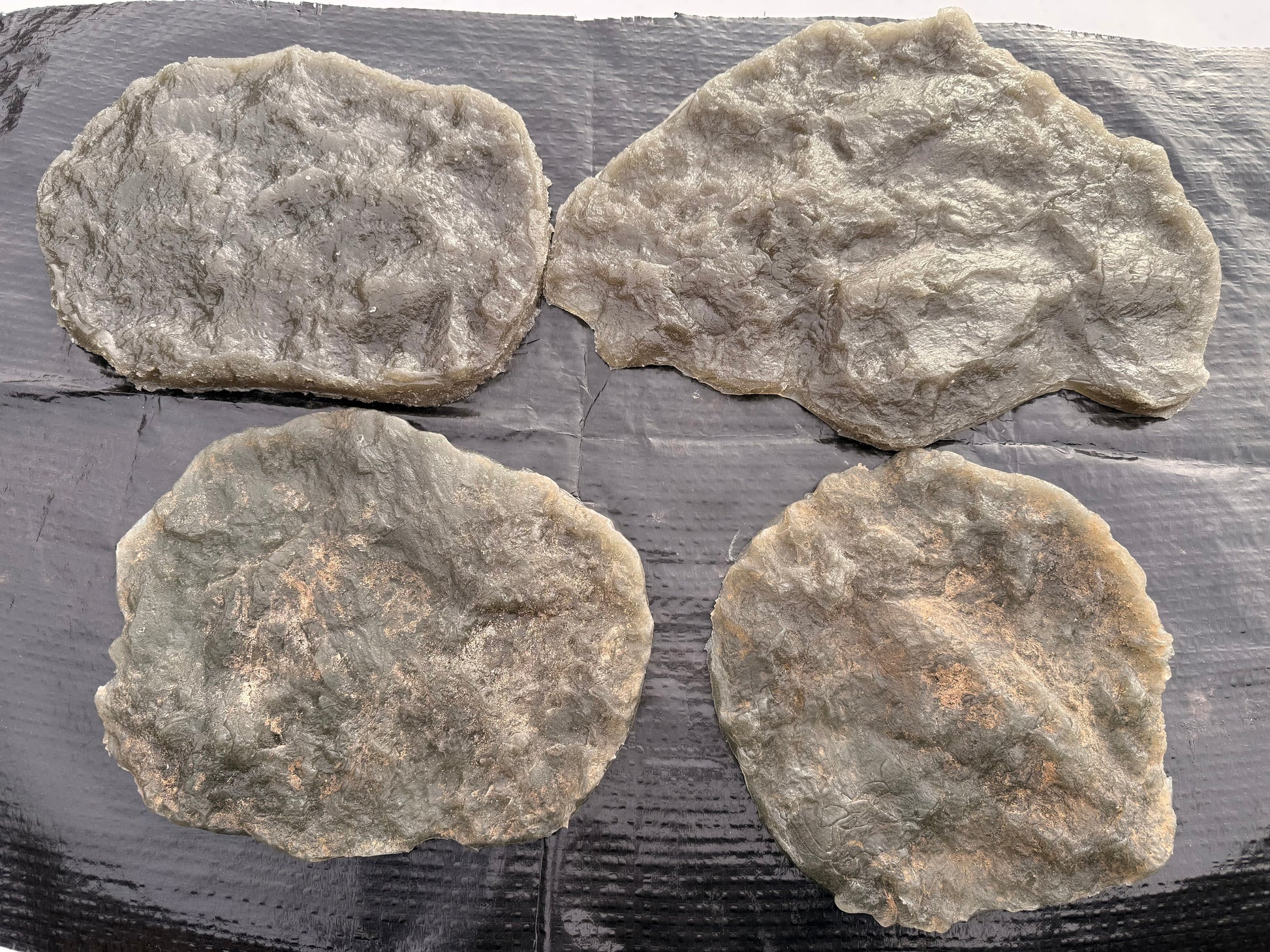 Four rough textured stamps on a dark surface