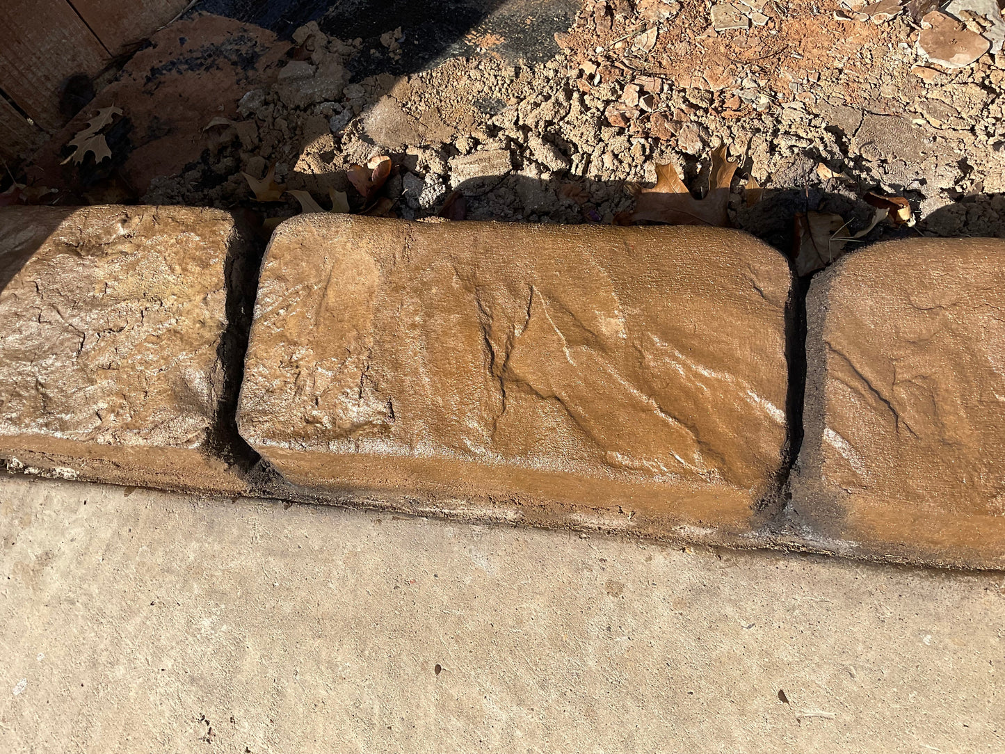 Palo Duro slate curbing brown earth tones in color with some deep black joint lines along a concrete walkway. Curbart Creations