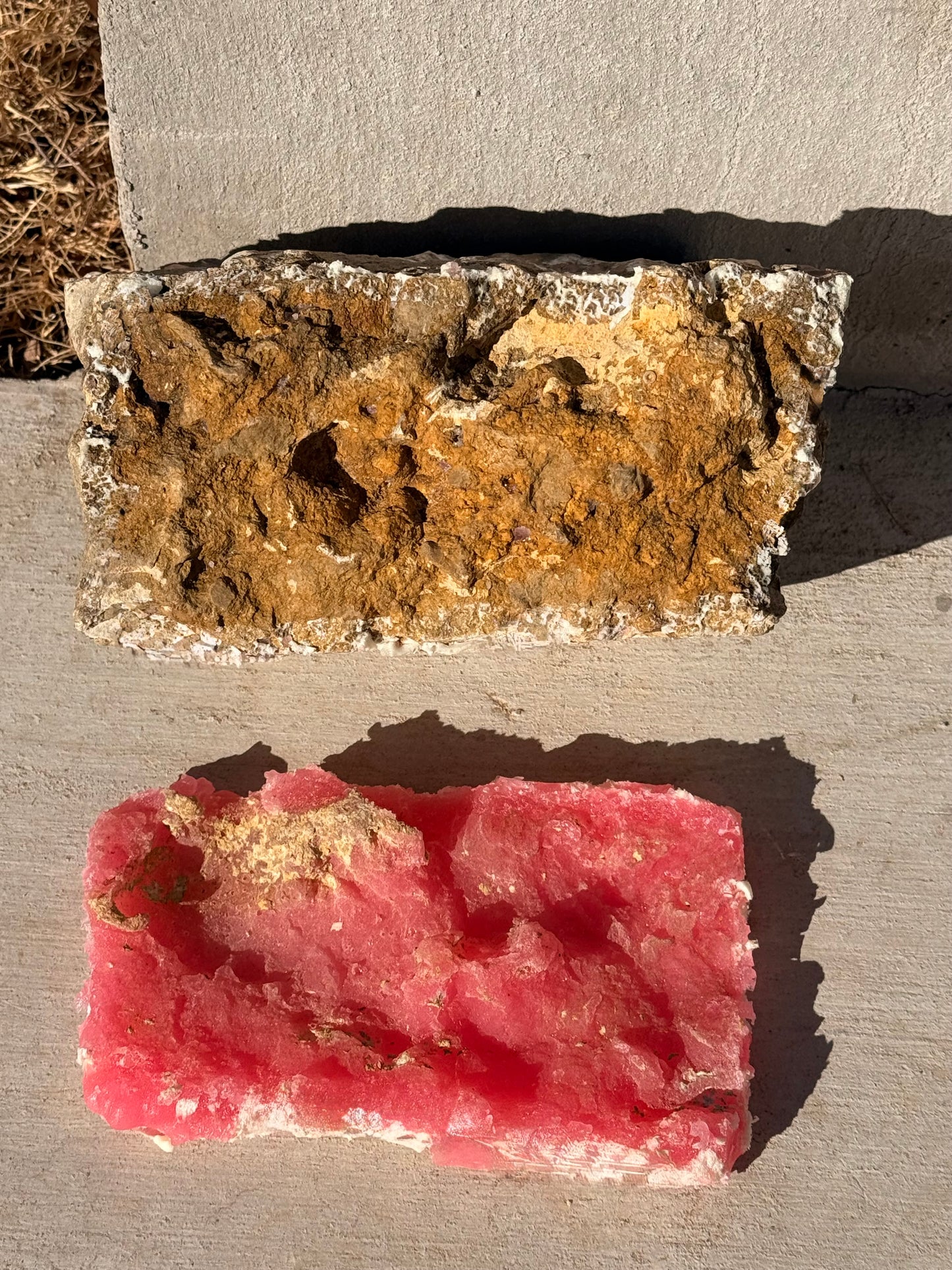 Weathered Crag concrete stamp along with the rock, one rust-colored and one pink, on a concrete surface.